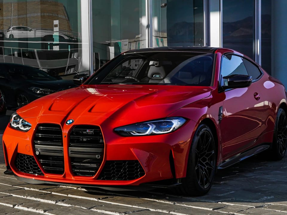 Красный BMW M4 у автосалона